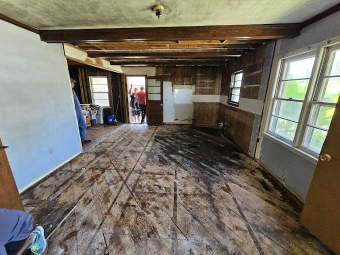 Abandoned house interior with damaged floor and walls.